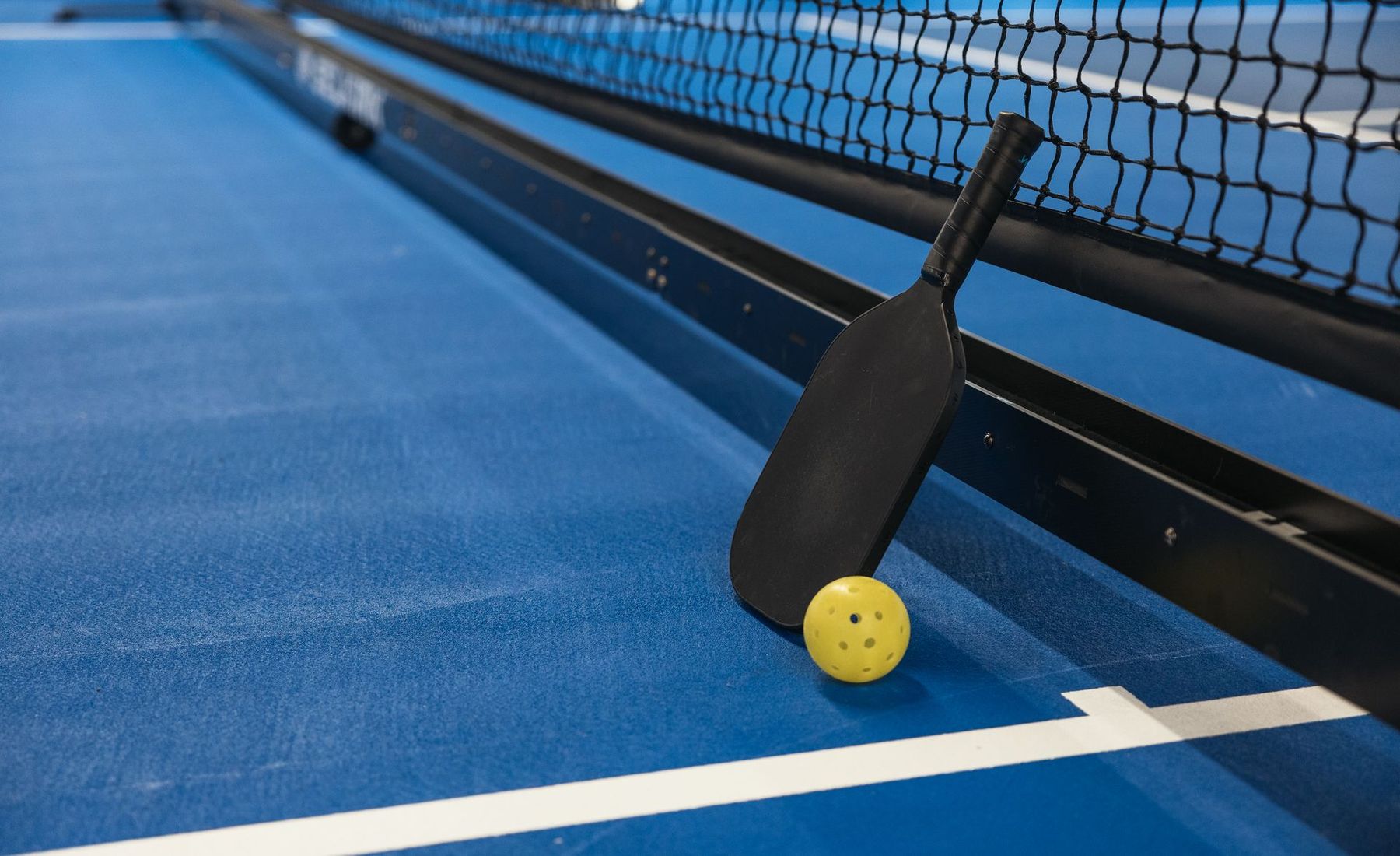 A paddle and ball resting by the net