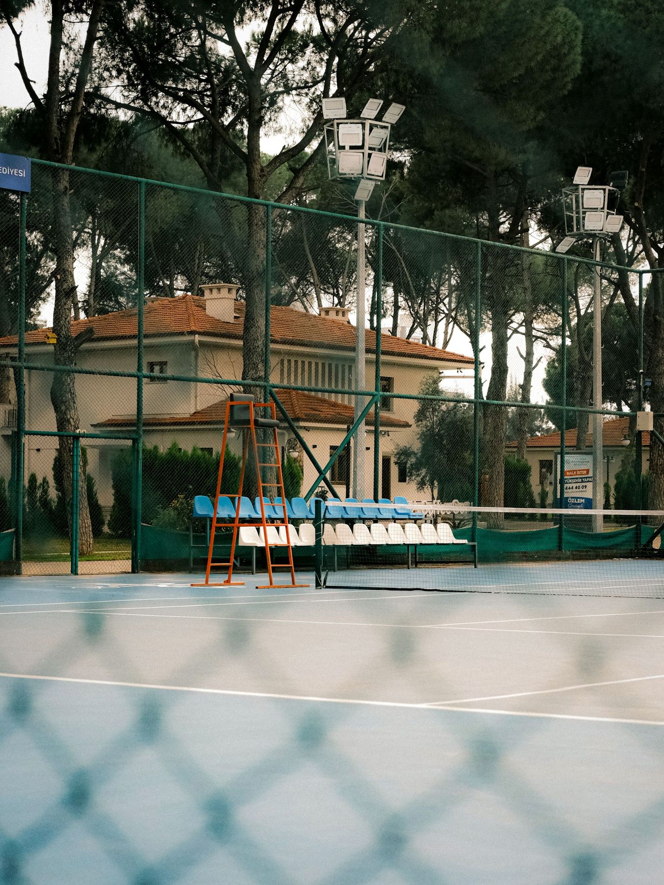 An outdoor court with trees, seating and floodlights