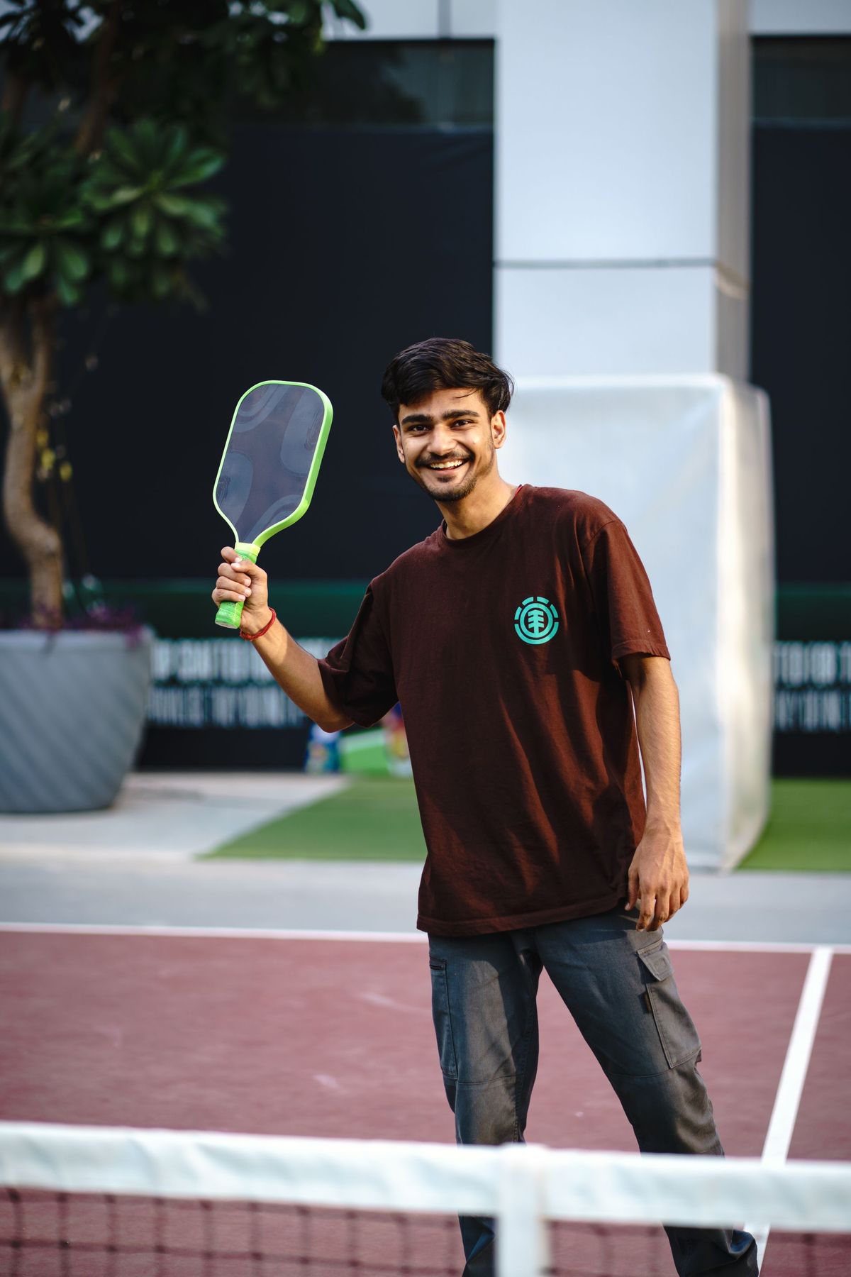 A smiling player with a paddle on an outdoor court